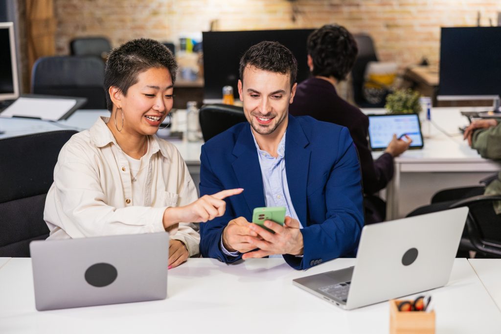 Two professionals collaborating while using a smartphone to explore a Message API integration in a modern office setting.
