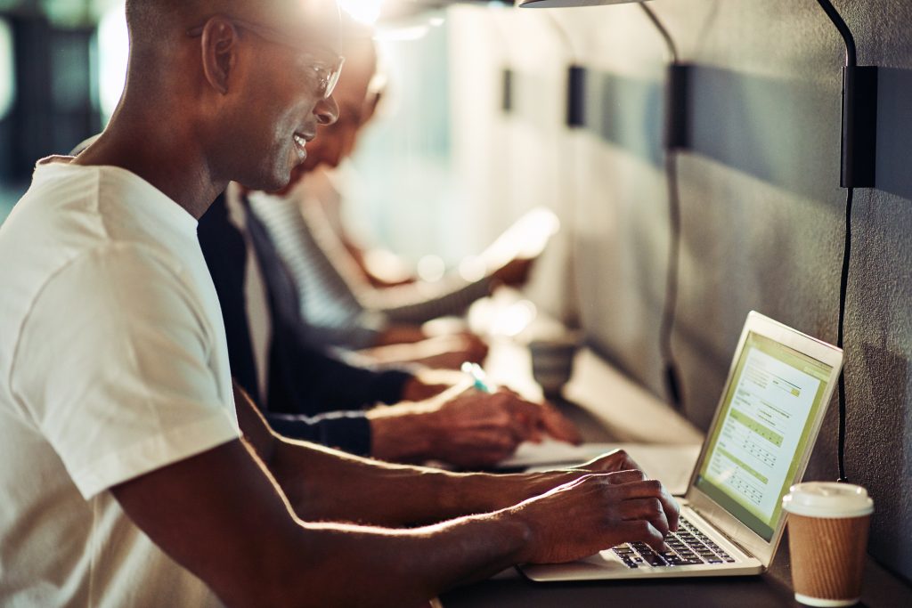 Developer coding on a laptop in a coworking space, testing a messaging API integration and monitoring rate limits and message delivery.