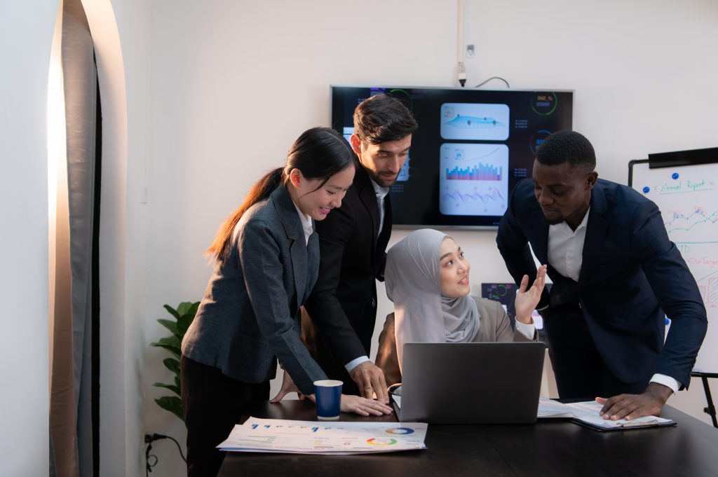 SMS Provider Malaysia: business team plans OTP and alerts, reviewing charts in office; PDPA and MCMC compliance in focus.