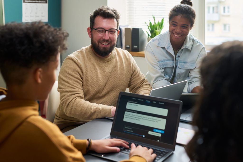 Team collaborating with laptops while discussing customer insights, representing SMS Service Malaysia for boosting feedback with SMS surveys.