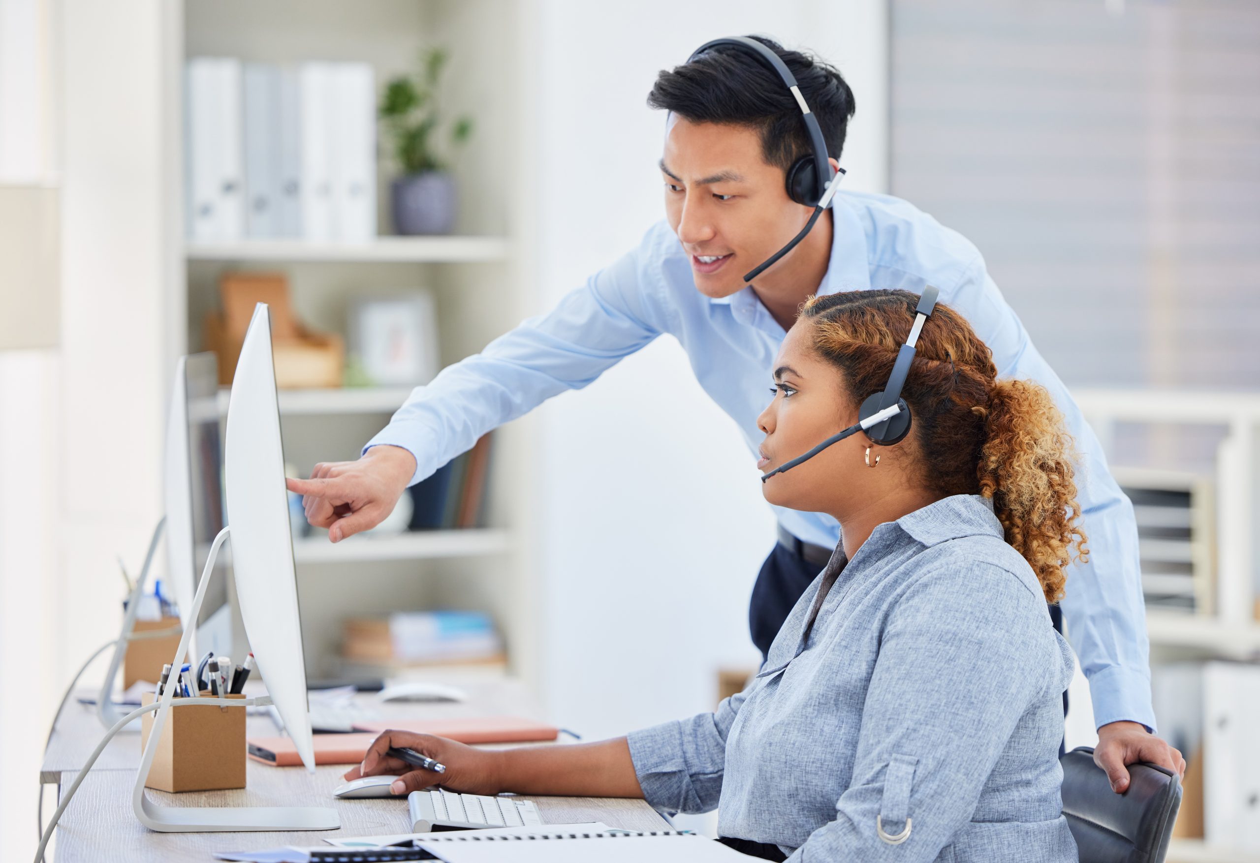Customer support agents with headsets discussing solutions, illustrating how a send SMS API helps scale customer support efficiently.