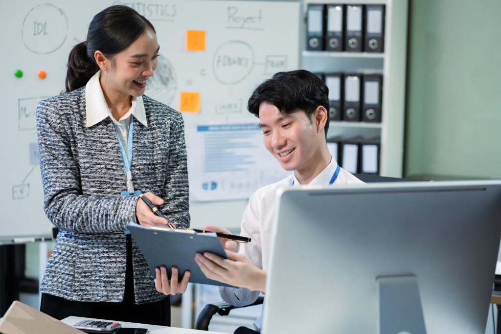 Two startup professionals discussing project strategies in an office, highlighting the importance of choosing a reliable SMS Provider Malaysia for business communication.