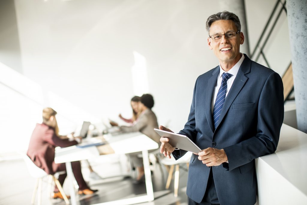 Professional businessman holding a tablet in a modern office representing reliable SMS Provider Malaysia services.