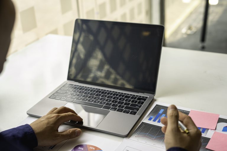 A person analysing marketing charts on a laptop, planning an SMS Service Malaysia campaign strategy.