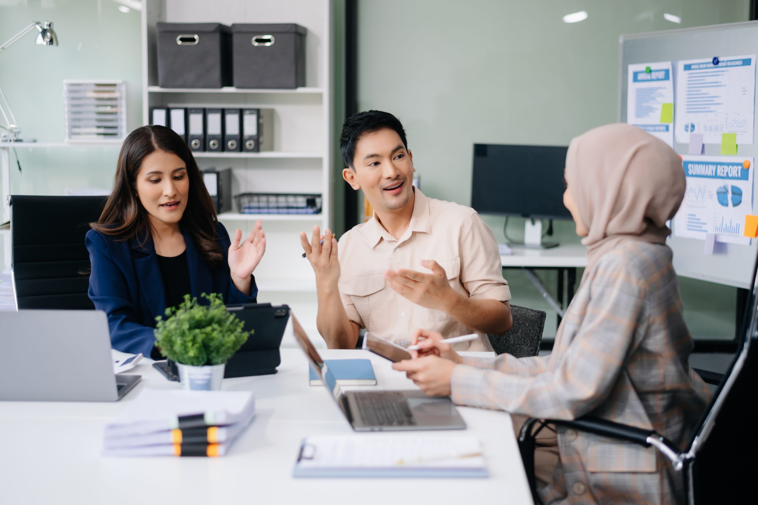 Three Malaysian professionals discussing business strategy in an office, representing a local SMS Provider Malaysia team.