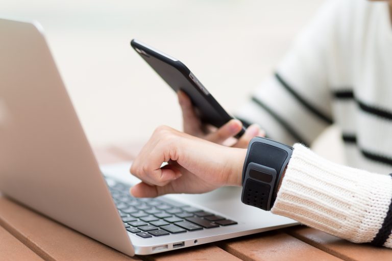 Person using a smartphone, smartwatch, and laptop simultaneously, showing seamless business communication powered by a Messaging API.