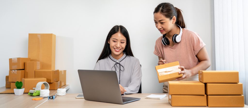 Two e-commerce staff preparing customer orders while managing updates using SMS Service Malaysia