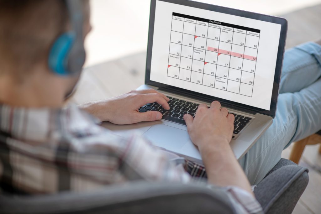 A person reviewing a digital calendar on a laptop to manage appointments using a Programmable SMS API.