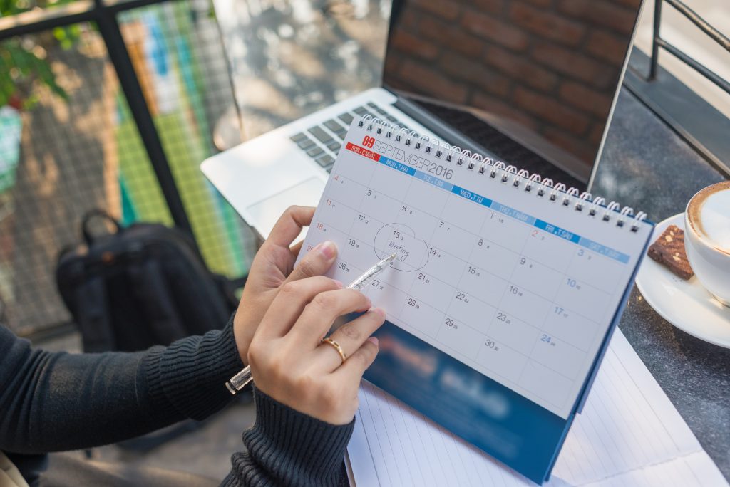 Person checking appointment date on a calendar, showing how SMS API Malaysia helps automate appointment reminders