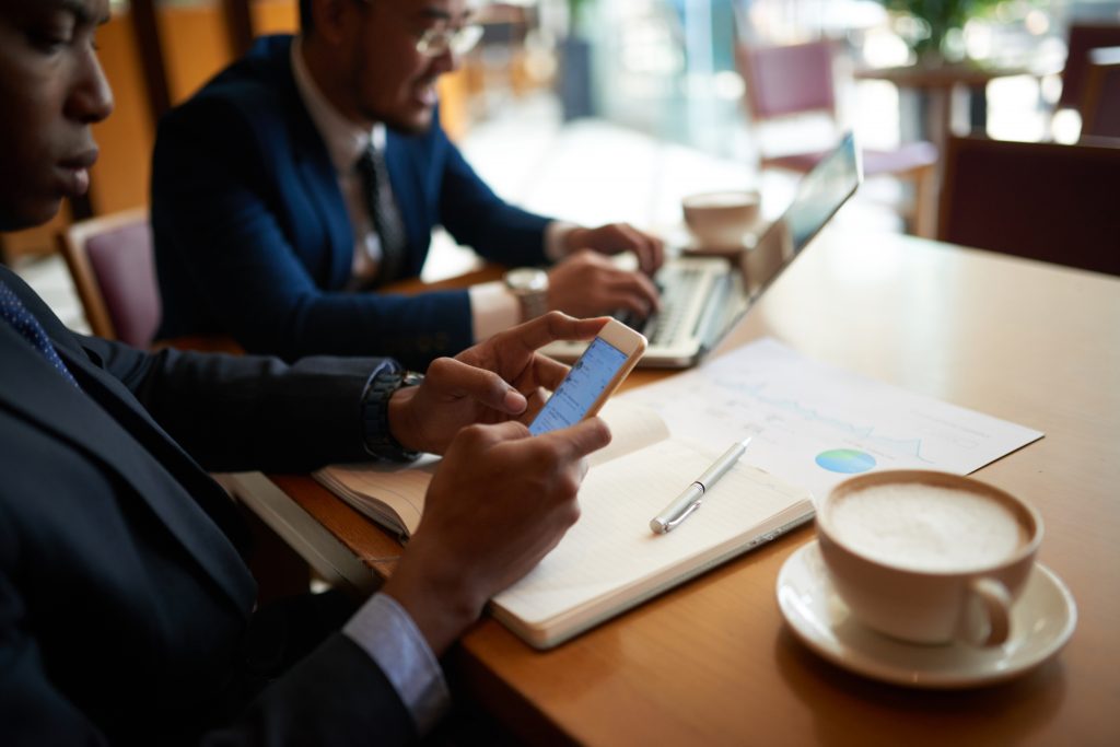 Business professionals reviewing mobile SMS campaign data during a marketing discussion for Bulk SMS Malaysia strategy