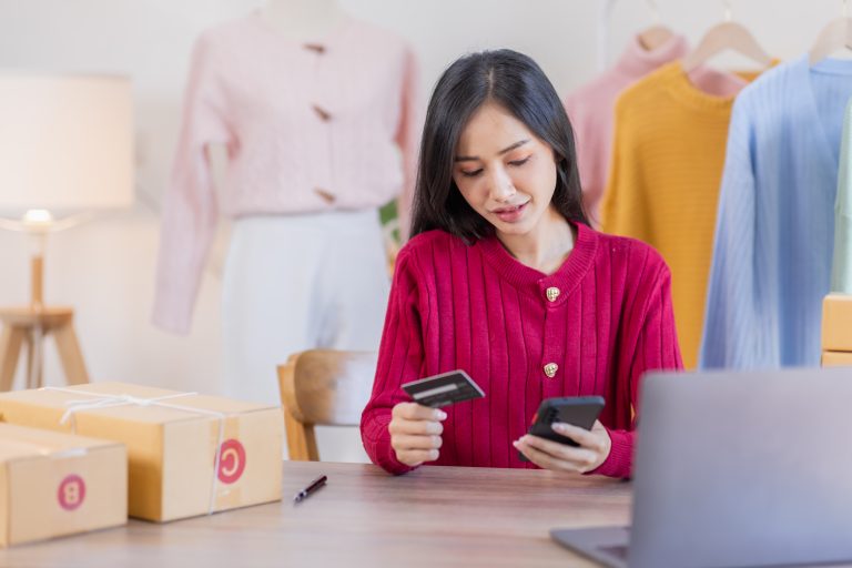 Woman managing an e-commerce order on her phone, showing how SMS Provider Malaysia supports mobile-first online sales