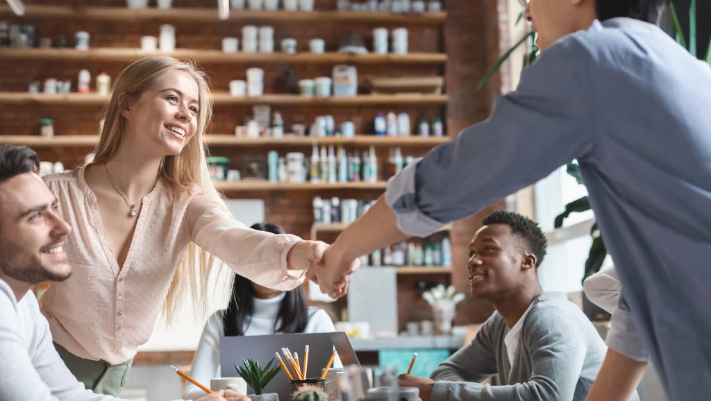 A business team shaking hands during a meeting, representing trust and customer engagement through SMS Service Malaysia.