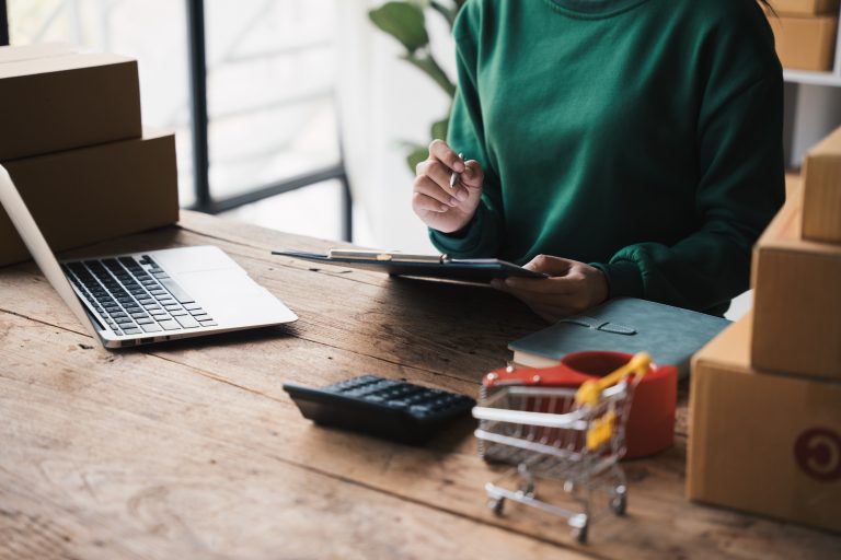 E-commerce seller managing online orders and inventory at desk, powered by SMS Provider Malaysia for real-time updates