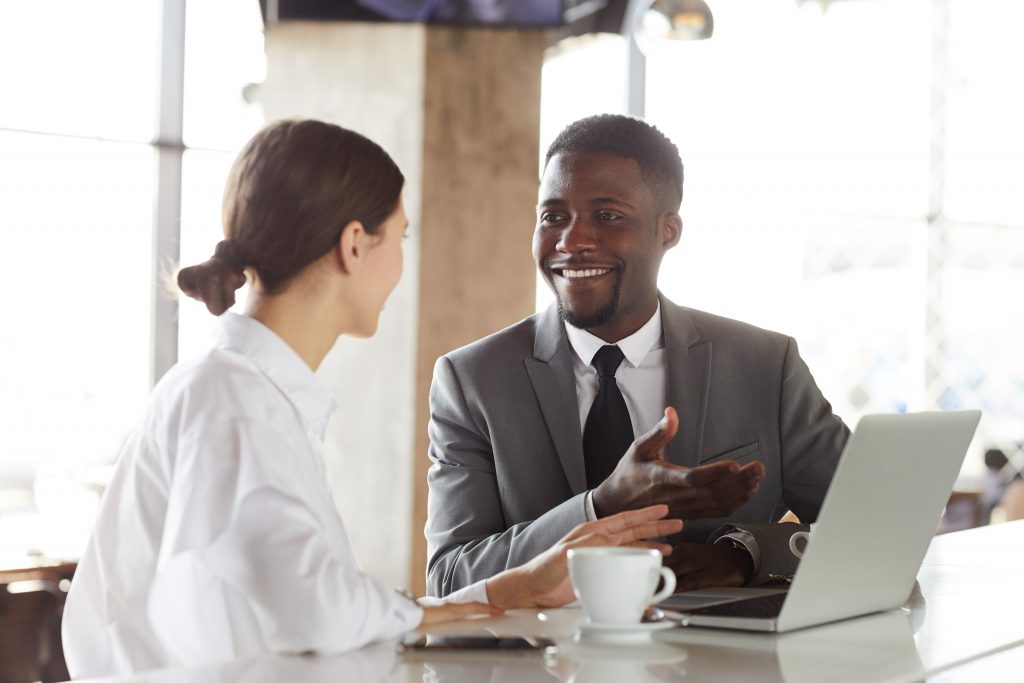 Business professionals discussing customer communication strategy using Bulk SMS Malaysia on a laptop in an office meeting.