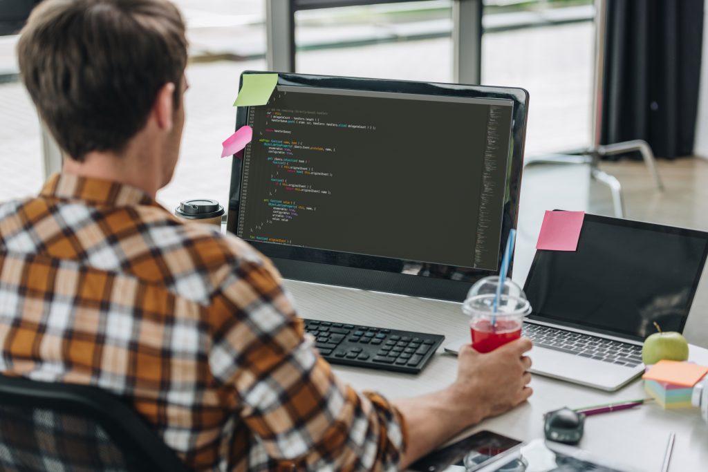 Developer working on code for programmable SMS API integration on desktop and laptop setup