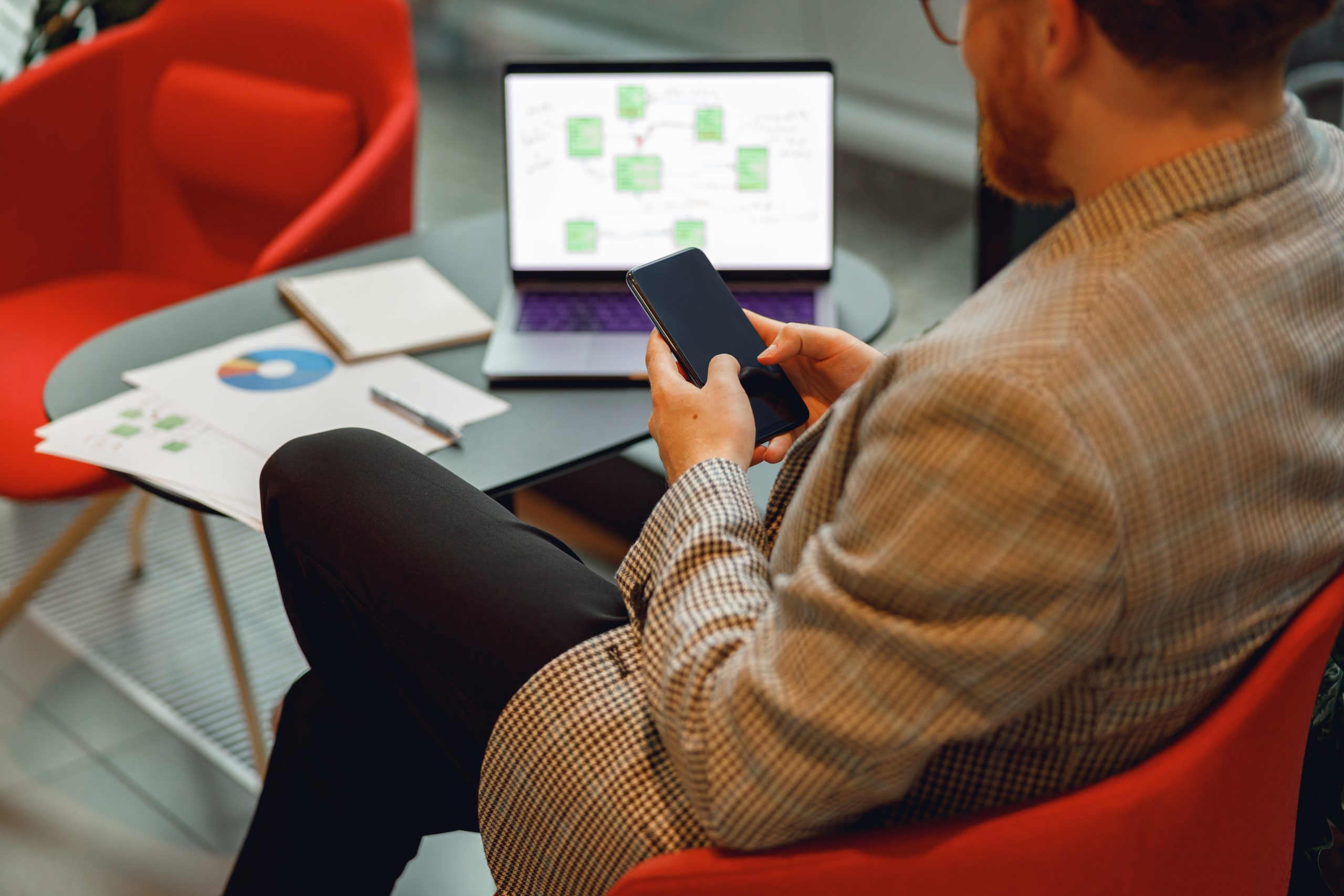 Enterprise professional using a smartphone with business system workflow on laptop