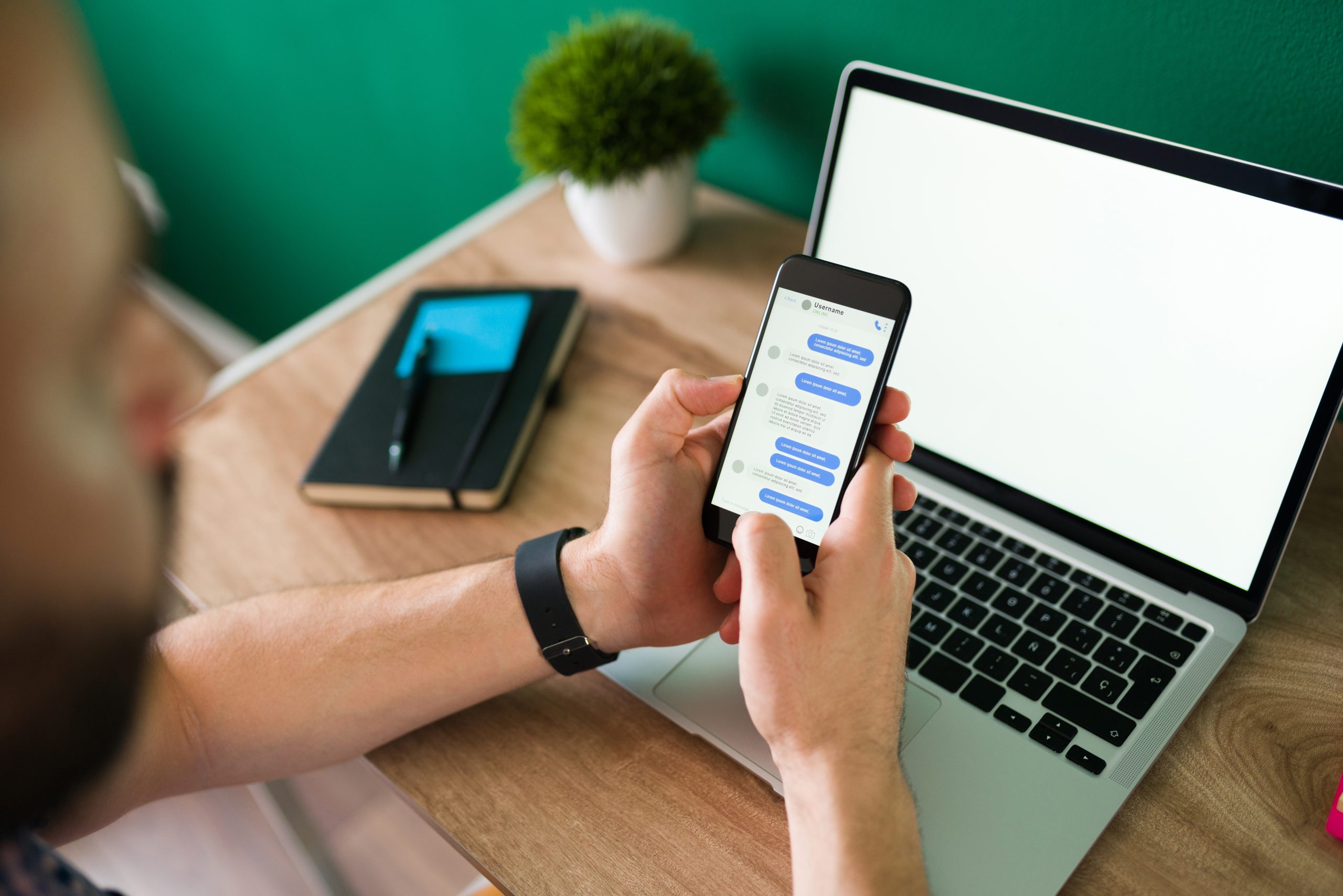 Developer using WhatsApp messaging on a mobile phone with a laptop