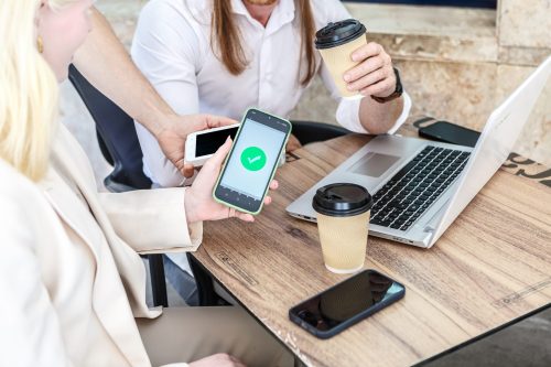 Business team reviewing WhatsApp Business API pricing on smartphones during a meeting.
